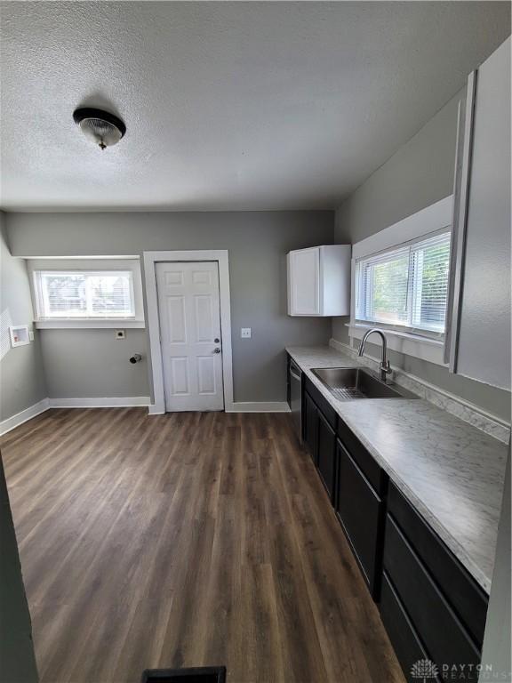 66 Barnett St Unit 64, Dayton, OH 45402 - kitchen featuring a sink, dark wood-style flooring, baseboards, stainless steel dishwasher, and white cabinetry