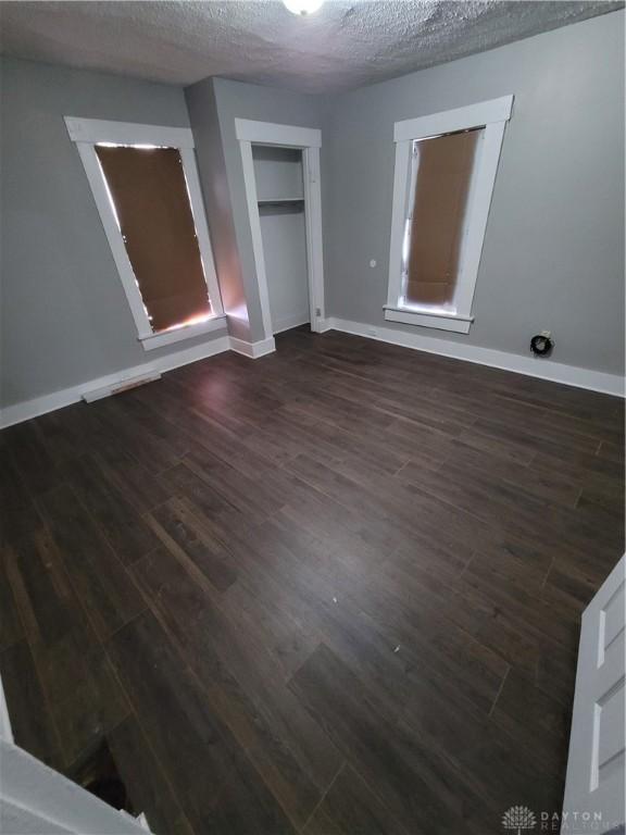 66 Barnett St Unit 64, Dayton, OH 45402 - unfurnished bedroom with dark wood-type flooring, baseboards, a closet, and a textured ceiling