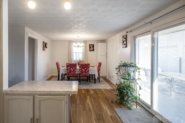 dining area featuring a textured ceiling, a notable chandelier, dark wood-style flooring, and baseboards