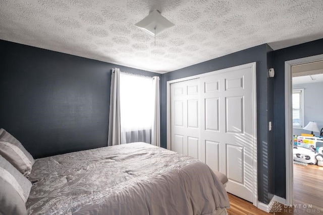bedroom featuring a textured ceiling, wood finished floors, and a closet