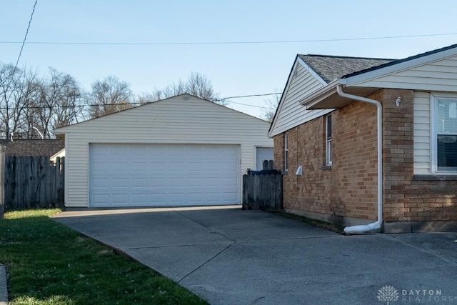view of home's exterior featuring an outbuilding, a detached garage, brick siding, and fence