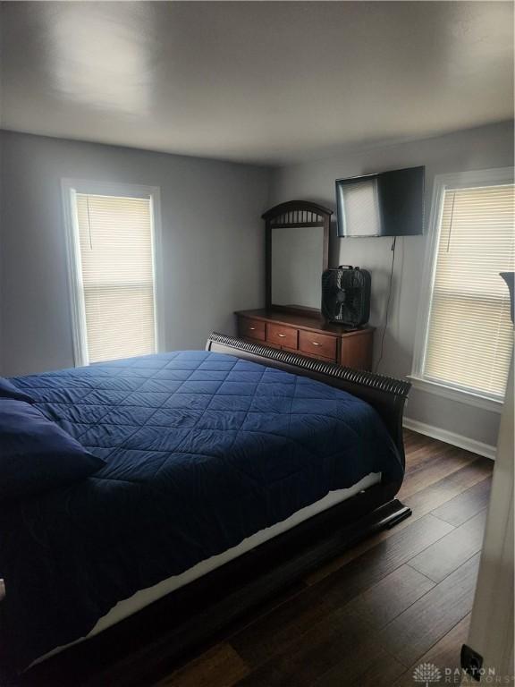 bedroom with baseboards, dark wood-style flooring, and multiple windows