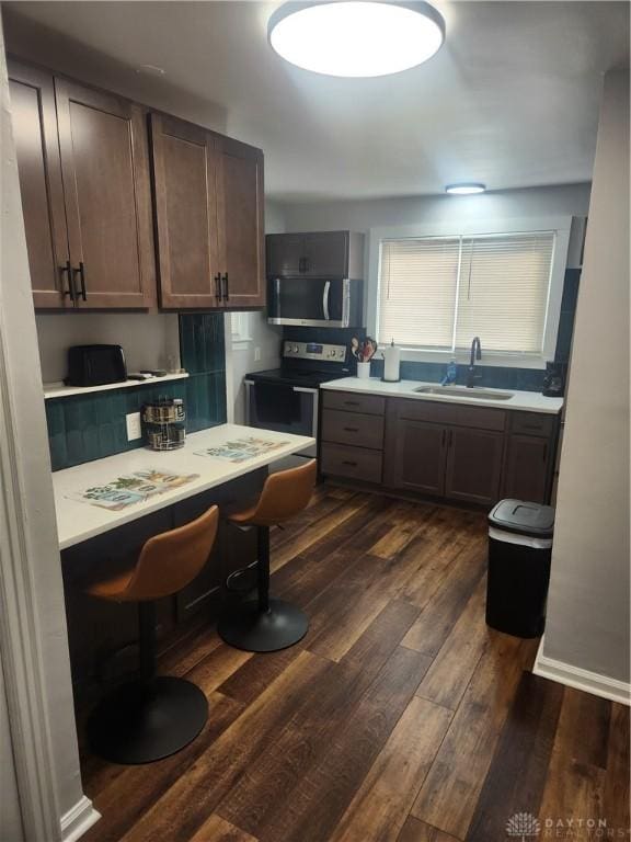 kitchen featuring appliances with stainless steel finishes, light countertops, dark wood-style floors, and a sink