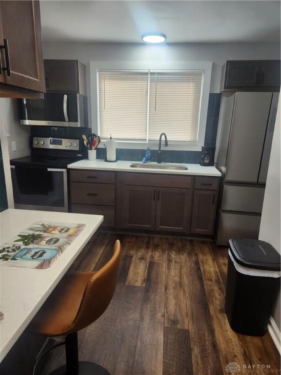 kitchen featuring light countertops, a sink, stainless steel appliances, and dark wood-type flooring