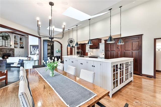 7177 Paul Ln, Liberty Twp, OH 45044 - dining room with baseboards, light wood-type flooring, a fireplace, a towering ceiling, and a notable chandelier