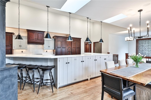 7177 Paul Ln, Liberty Twp, OH 45044 - kitchen with a skylight, decorative light fixtures, light countertops, light wood finished floors, and a notable chandelier