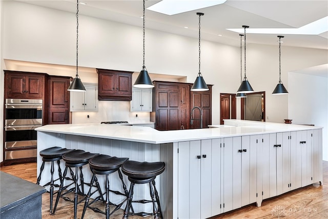 7177 Paul Ln, Liberty Twp, OH 45044 - kitchen with a warming drawer, double oven, light wood finished floors, a sink, and high vaulted ceiling