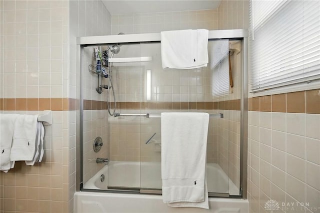 full bathroom with combined bath / shower with glass door and tile walls
