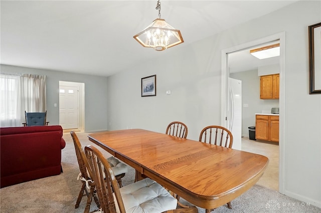 dining area featuring light colored carpet, a chandelier, and baseboards