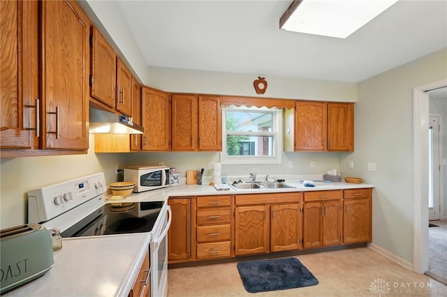 kitchen featuring brown cabinets, white appliances, under cabinet range hood, and a sink