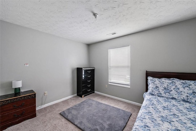 carpeted bedroom featuring baseboards, visible vents, and a textured ceiling