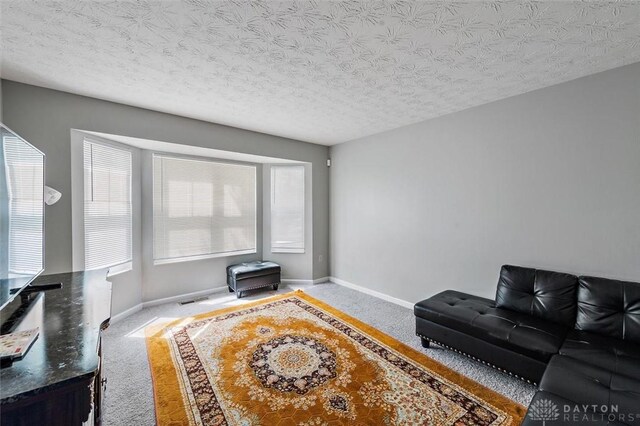 carpeted living area featuring a textured ceiling, visible vents, and baseboards