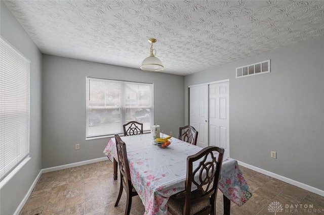 dining room featuring a textured ceiling, visible vents, baseboards, and a healthy amount of sunlight