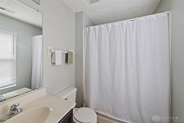 bathroom with toilet, visible vents, vanity, and a textured ceiling