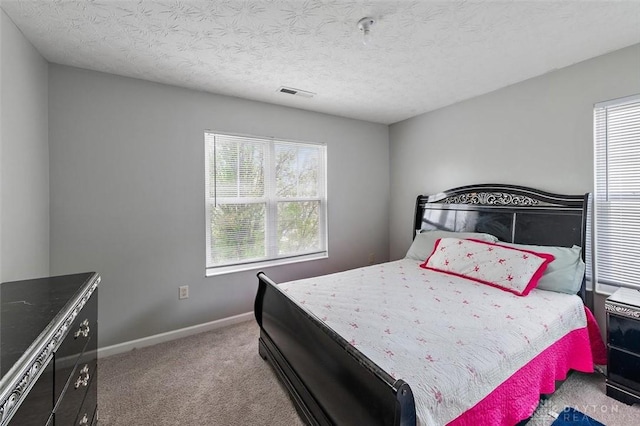 carpeted bedroom featuring baseboards, visible vents, and a textured ceiling