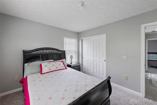 carpeted bedroom featuring baseboards, a textured ceiling, and a closet