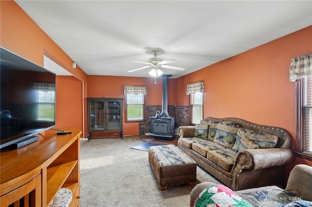 living room featuring a ceiling fan, carpet flooring, and a wood stove