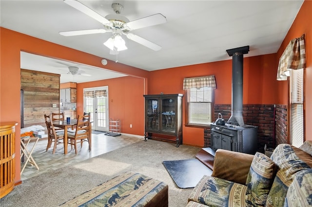 living area with a wealth of natural light, french doors, a ceiling fan, and a wood stove