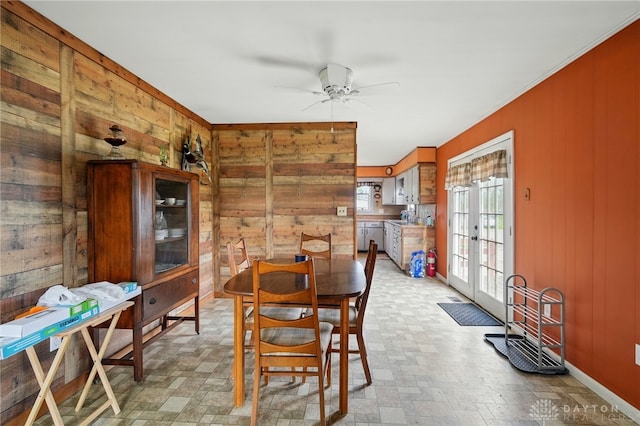 dining space featuring wooden walls, french doors, a ceiling fan, and ornamental molding