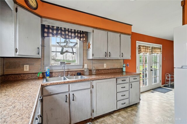 kitchen featuring light floors, a sink, freestanding refrigerator, and tasteful backsplash