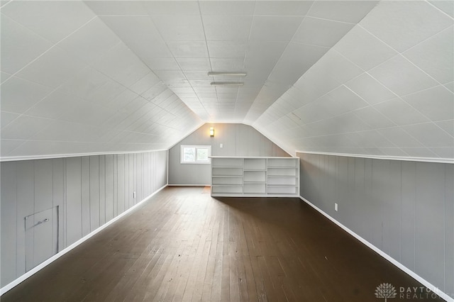 additional living space featuring lofted ceiling, wood walls, hardwood / wood-style flooring, and baseboards