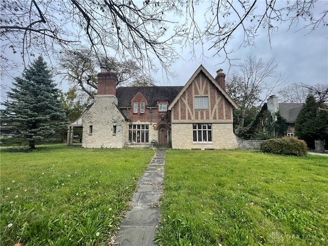 rear view of house featuring a lawn, brick siding, and a chimney