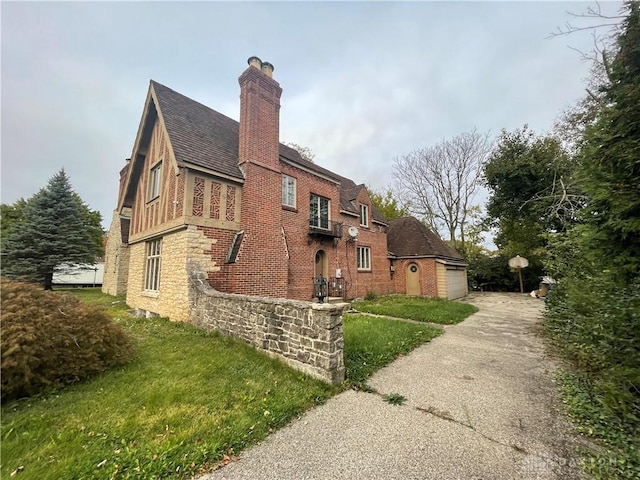 view of side of property with driveway, a chimney, a lawn, and a shingled roof