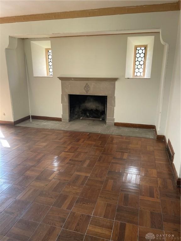 unfurnished living room with baseboards and a fireplace