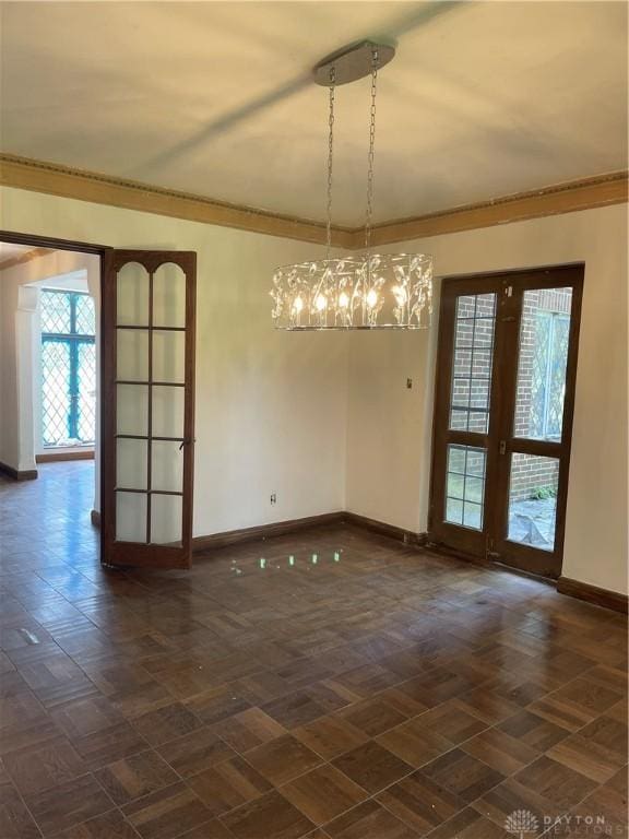unfurnished dining area with crown molding, a notable chandelier, and baseboards