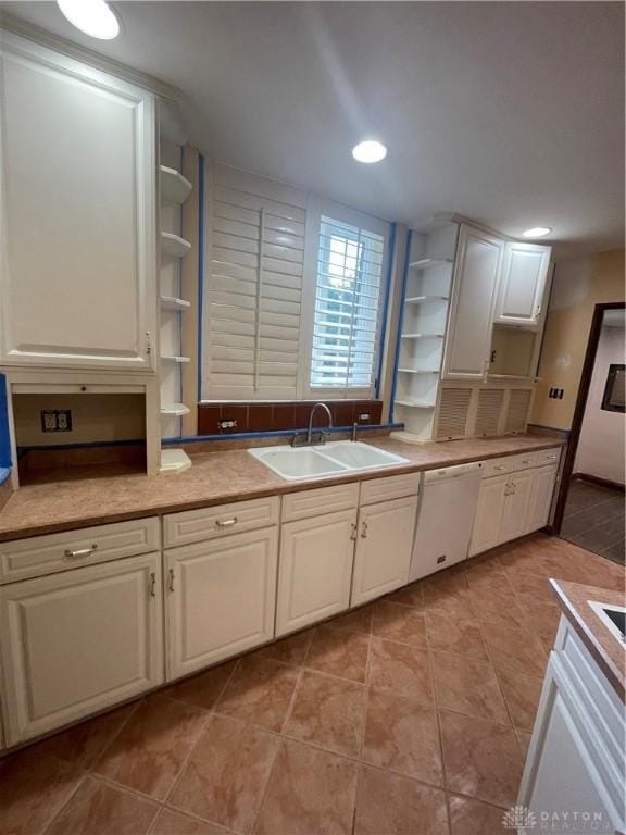 kitchen with light tile patterned flooring, open shelves, white dishwasher, and a sink