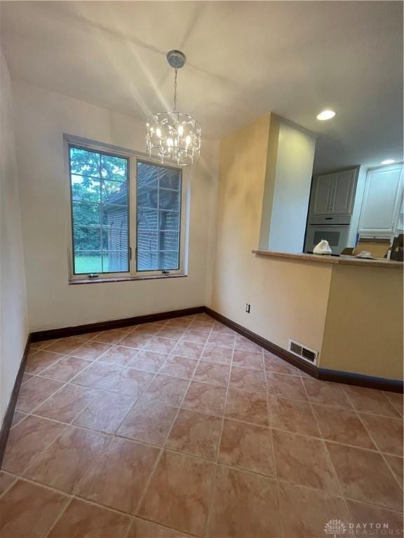unfurnished dining area featuring baseboards, visible vents, light tile patterned floors, and a notable chandelier