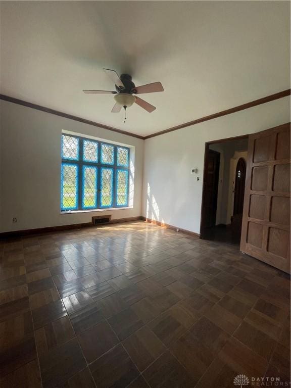 spare room featuring visible vents, a ceiling fan, ornamental molding, and baseboards
