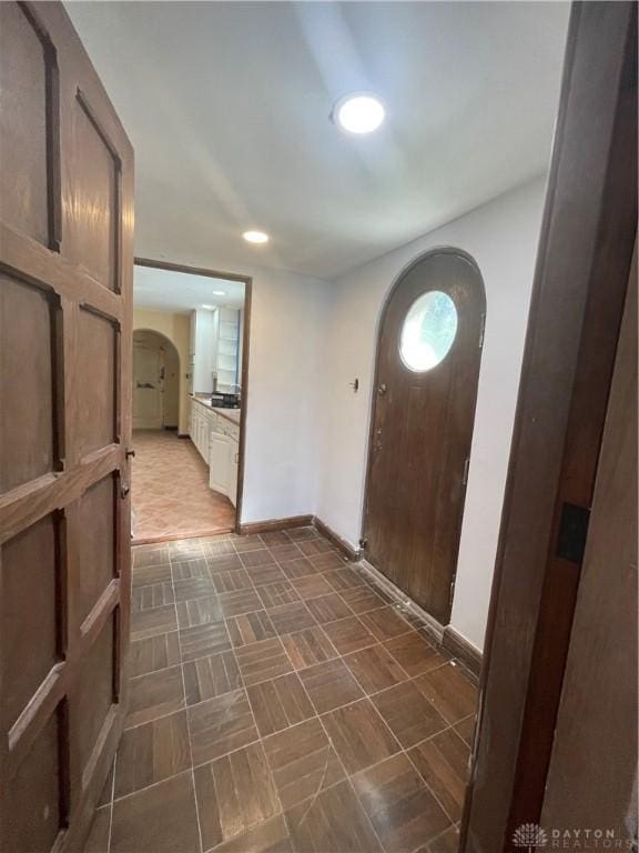 foyer entrance with baseboards, recessed lighting, and arched walkways