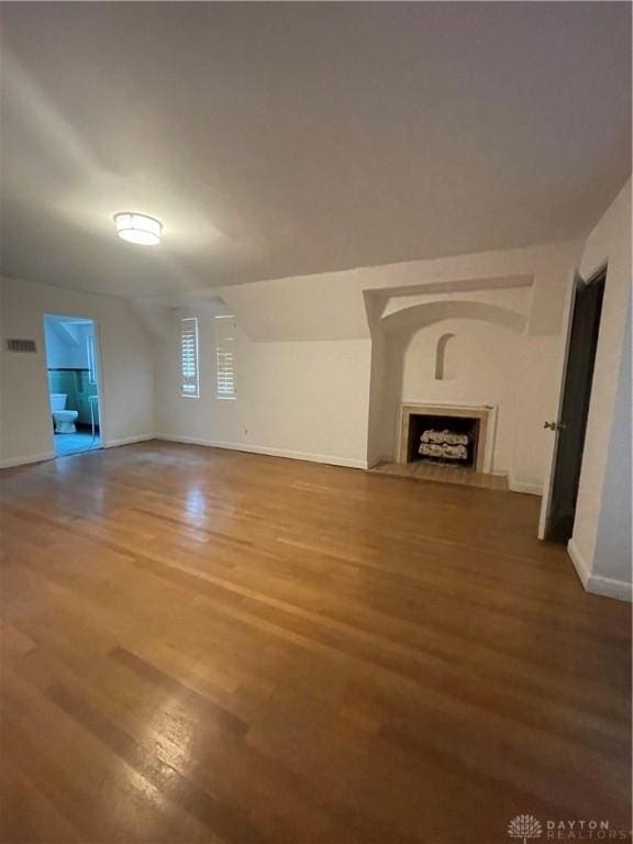 unfurnished living room with baseboards, wood finished floors, and a fireplace