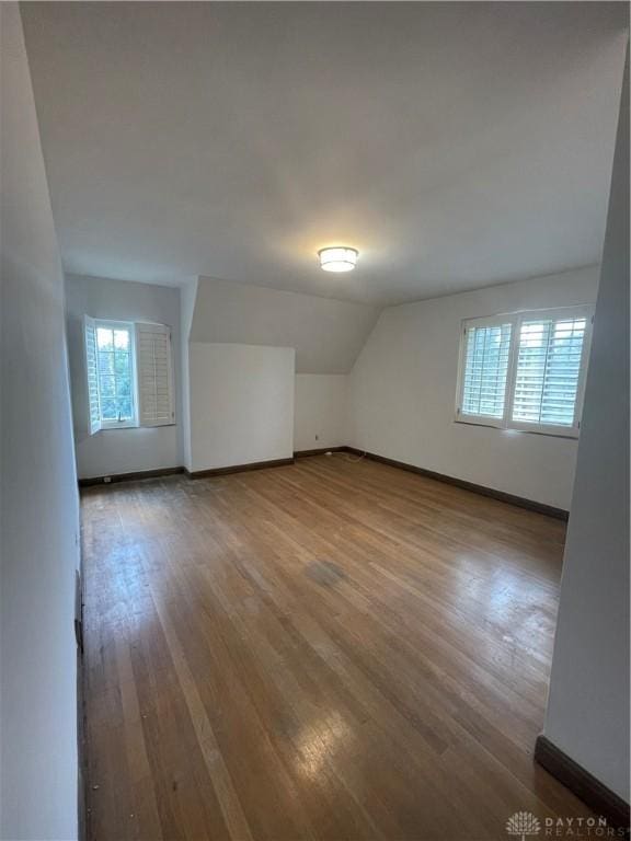 additional living space featuring lofted ceiling, wood finished floors, and baseboards