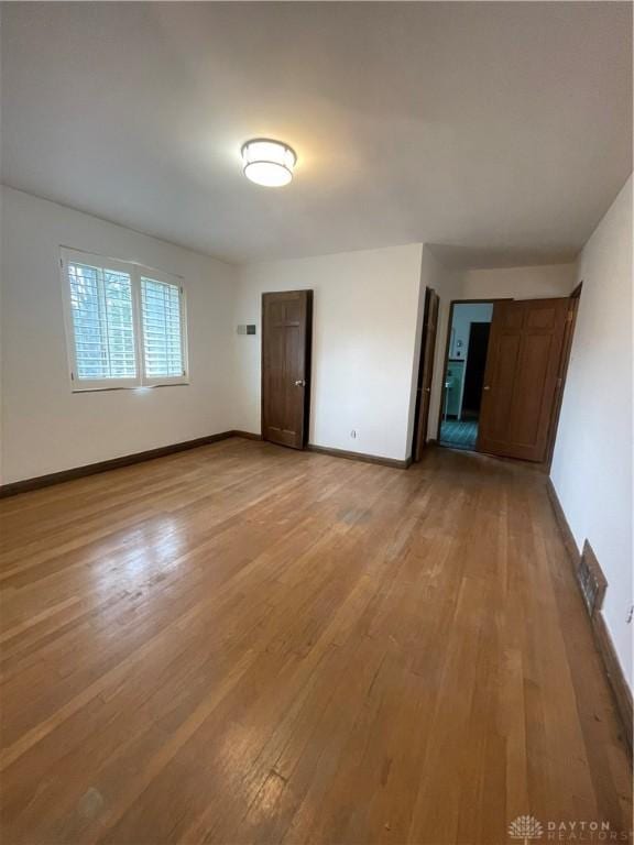spare room featuring light wood-style floors and baseboards