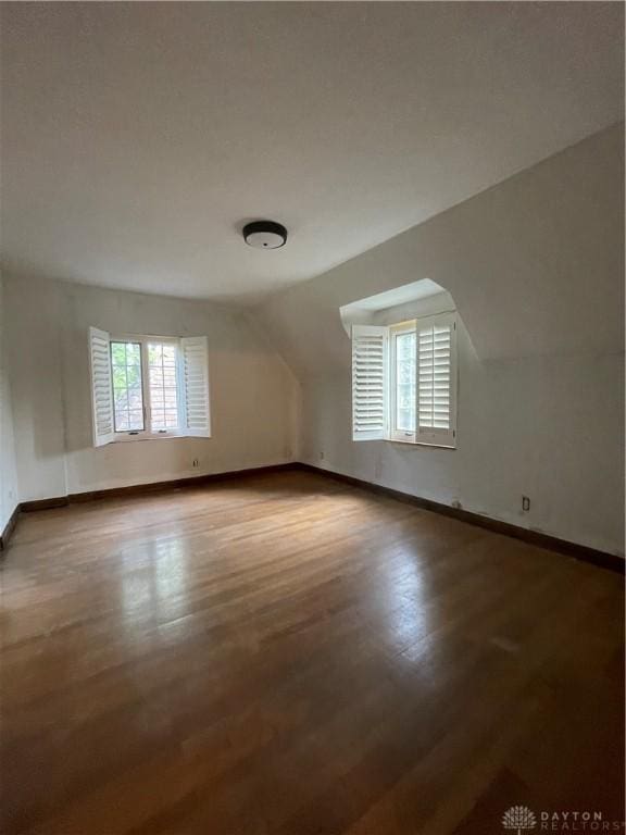 bonus room featuring baseboards, wood finished floors, and vaulted ceiling