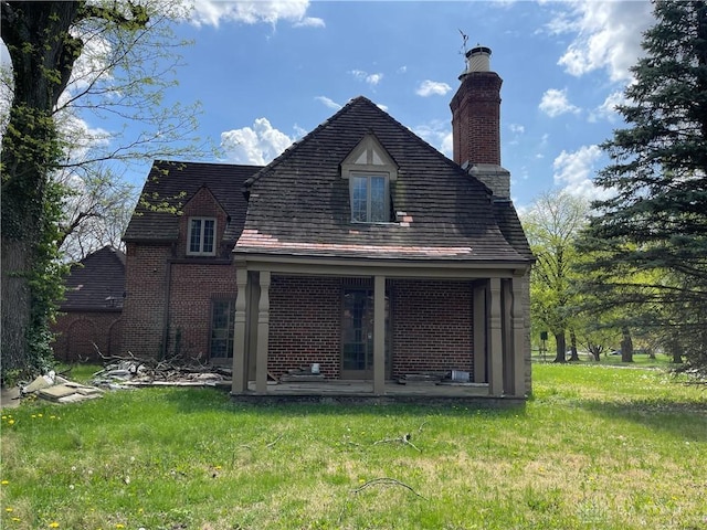 back of property with a lawn, a chimney, a patio, and brick siding