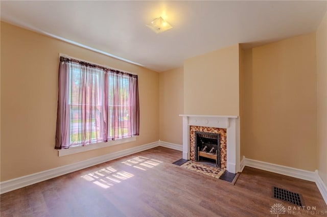 unfurnished living room featuring baseboards, visible vents, and wood finished floors