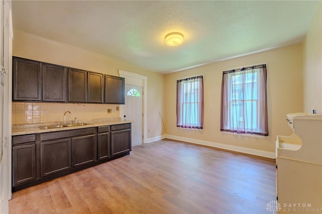 kitchen featuring dark brown cabinetry, a wealth of natural light, light wood-style flooring, and a sink