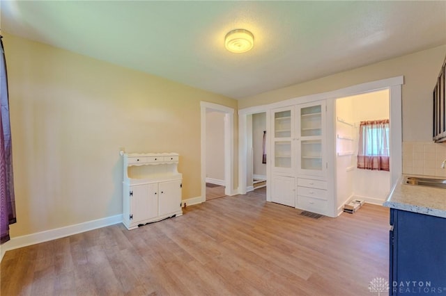 laundry area featuring visible vents, baseboards, light wood finished floors, and a sink