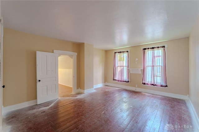 unfurnished room with baseboards and wood-type flooring