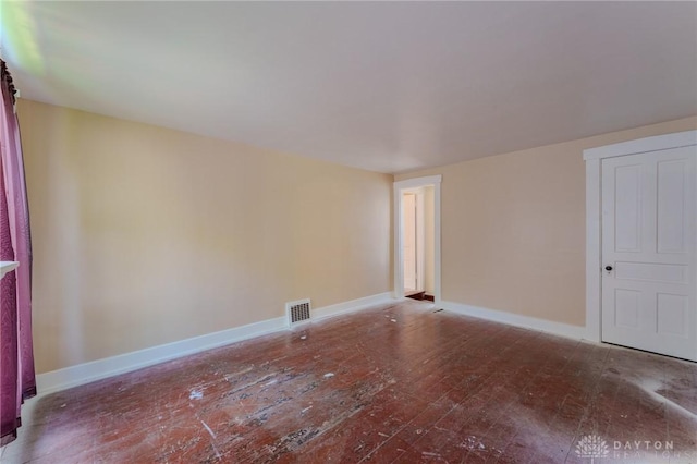 unfurnished room with baseboards, visible vents, and wood-type flooring
