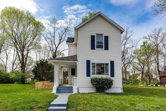 traditional home featuring a shingled roof and a front lawn