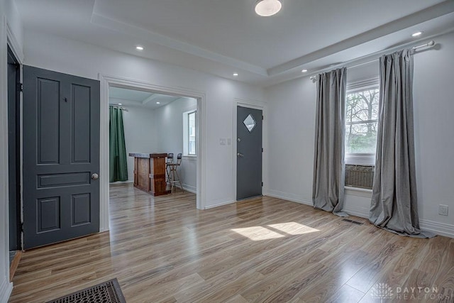 entryway with recessed lighting, light wood finished floors, baseboards, visible vents, and a raised ceiling