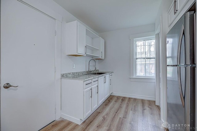 kitchen featuring a sink, light wood-style floors, open shelves, white cabinets, and freestanding refrigerator
