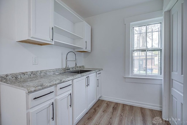 kitchen featuring white cabinetry, a sink, a wealth of natural light, and light wood-style floors