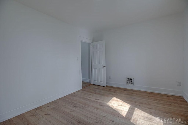 spare room featuring visible vents, light wood-style flooring, and baseboards
