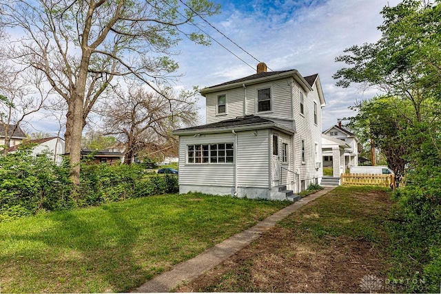 rear view of house featuring a chimney, fence, and a yard