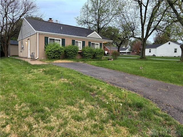 view of front facade with a front lawn, a chimney, and brick siding